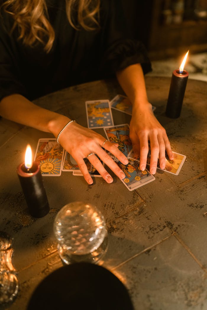 Mastering the First Impression: Your intriguing post title goes here A woman engaging in a tarot card reading with candles and a crystal ball on a dimly lit table.